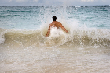 Tanned man jumping in the waves blue ocean