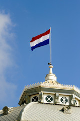 Fototapeta premium Dutch flag waving on the roof of Kurhaus hotel