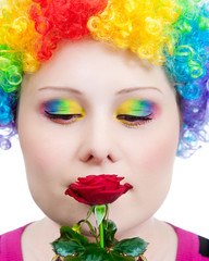 Clown with rainbow make up smelling rose