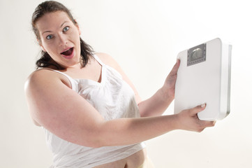 Übergewichtige erwachsene Frau hält eine Waage