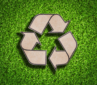 Recycle sign on green grass background