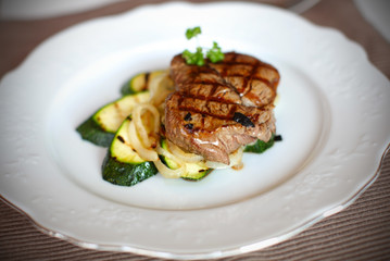 File mignon on grilled zucchini and onion