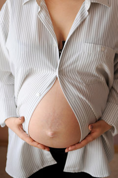 belly of a pregnant woman with her hands on it