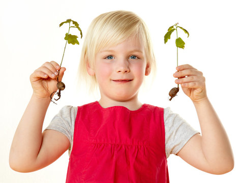 Little blond girl holding small plants in her hands