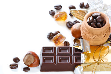 Coffee beans, chocolate, hazelnuts and brown sugar on a white.