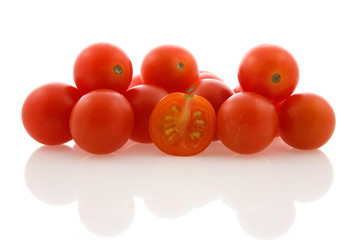 pile of small red  tomatoes with reflection on white