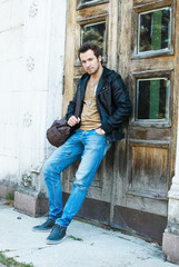 Obraz premium casual student holding his bag in his black leather jacket near
