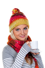 Frau mit Haube wärmt sich mit heißem Tee
