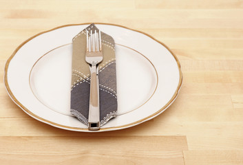 Knife and fork with white plate on wooden table