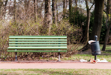 Parkbank mit überfülltem Mülleimer