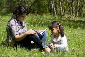 Teenage girl reads a story to little sister