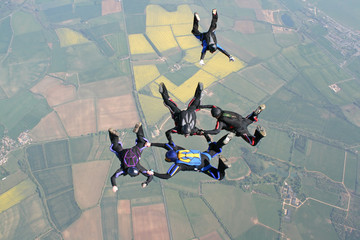 Five skydivers in freefall doing formations
