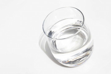 Bicchiere di vetro con acqua su sfondo bianco