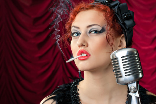redhead woman smoking cigarette near vintage microphone