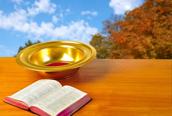 Offering plate on table with bible and bright background