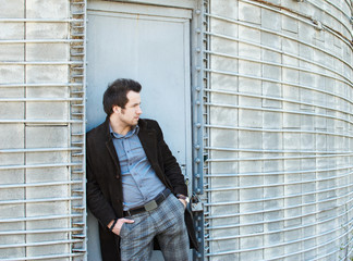 handsome guy standing alone in the farm in front of grey wall