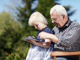 Grandfather and granddaughter playing with touchpad