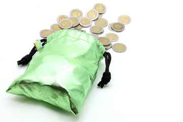 coins spilling out from green money bag or purse isolated on whi