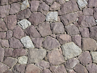 Stonewall, dry set masonry. Interlocking natural stones are forming a stone wall.