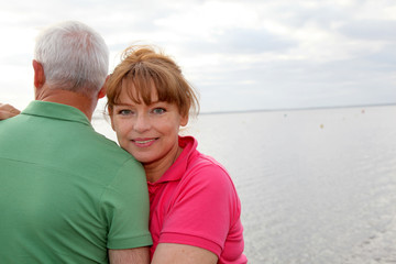 Fototapeta na wymiar Portrait of senior couple standing by a lake