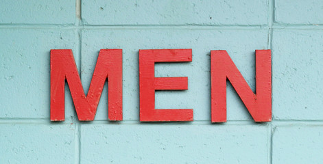 MEN in red against an aqua blue painted wall