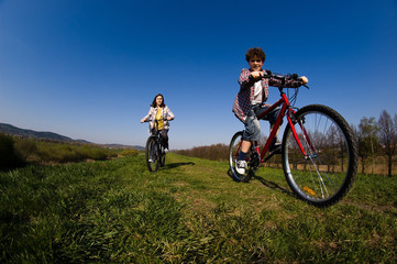 Obraz premium Girl and boy riding bike