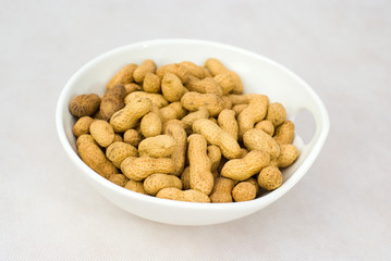 Pile of ripe crude peanuts in white bowl