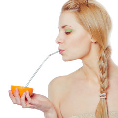 woman drinking juice direct from an orange fruit using a straw