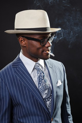 Fototapeta na wymiar Black man with blue striped suit and white hat smoking cigarette