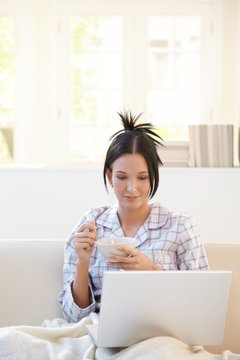 Woman having cereal looking at laptop