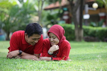 muslim asian couple reading book on green grass