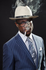 Black man with blue striped suit and blue hat smoking cigarette
