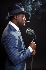 Fototapeta na wymiar Black man with blue striped suit and hat singing. Jazz musician