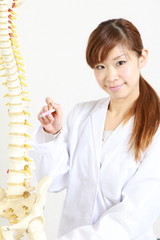 Chiropractor using a plastic model to explain about spine