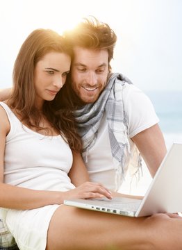 Young couple using laptop on the beach