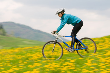 Spring bike riding - woman downhill on bike in dandelion