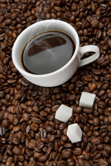 Coffee cup with sugar on roasted beans