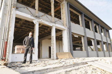 Mann auf der Baustelle vor entkernter Fassade - obrazy, fototapety, plakaty