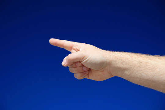Person zeigt mit dem Finger vor blauem Himmel
