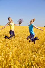 Fototapeta na wymiar beautiful girls jumps in golden field