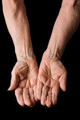 Hands of the old woman on a black background