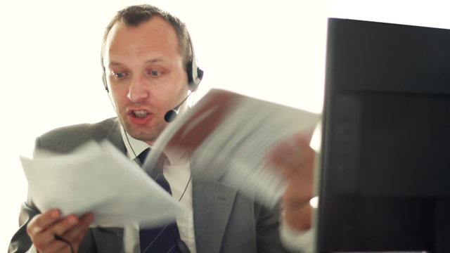 Angry businessman with headset and documents screaming