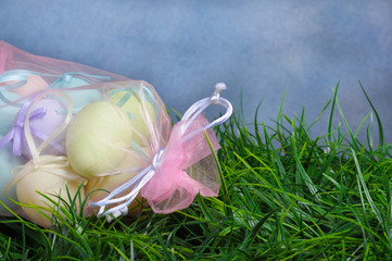 Easter eggs in pink bag, green grass with copy space and blue ba