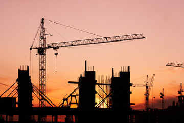 construction site with construction cranes at sunset