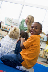 Kindergarten teacher reading to children in library, boy looking