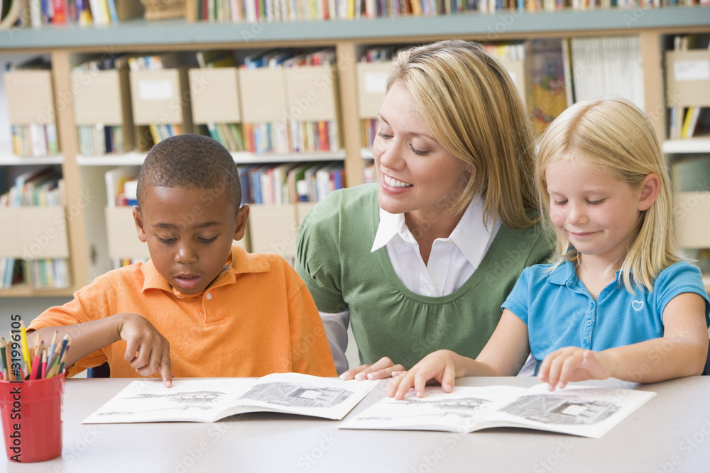 Wall mural Kindergarten teacher helping students with reading skills