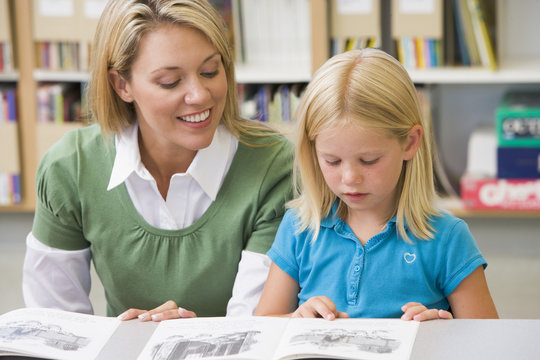 Kindergarten Teacher Helping Student With Reading Skills