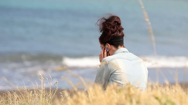 Mujer en la playa hablando por teléfono