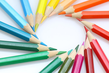 Color pencils in arrange in color wheel colors on white backgrou