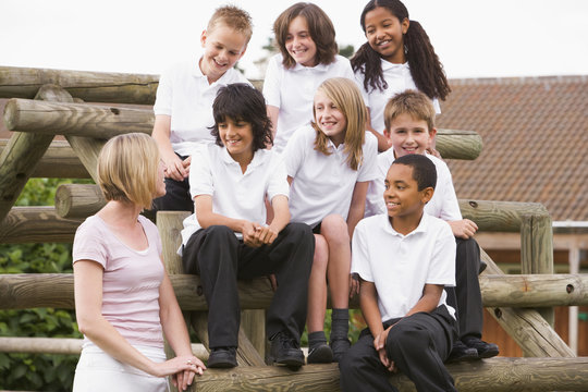 School children sitting on benches outside with their teacher